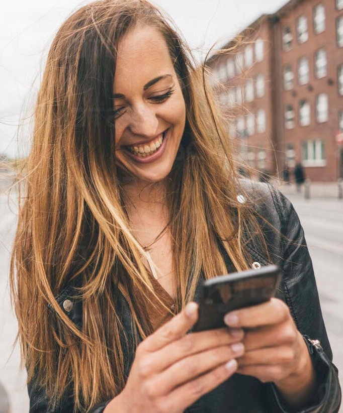 Happy young woman using cell phone in the city